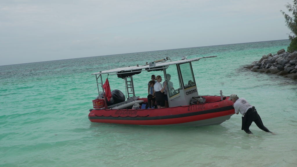 A scientist pushes a research boat off the shore