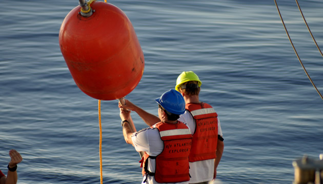 Scientists work with buoys aboard a research vessel